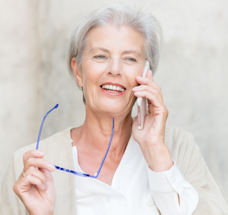 An elderly lady on the mobile phone call in front of a wall