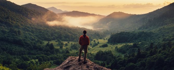 A person standing on a mountain top looking into the distance.